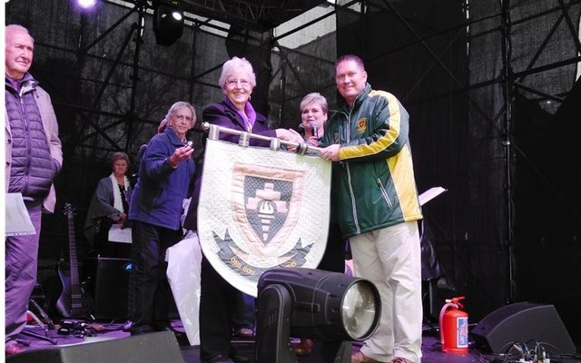 Olga Swanepoel oorhandig die skoolwapen van Bekker Landbou HoÃ«rskool, wat sy spesiaal gekwilt het, aan die skoolhoof tydens die skool se 80-jarige feesvieringe